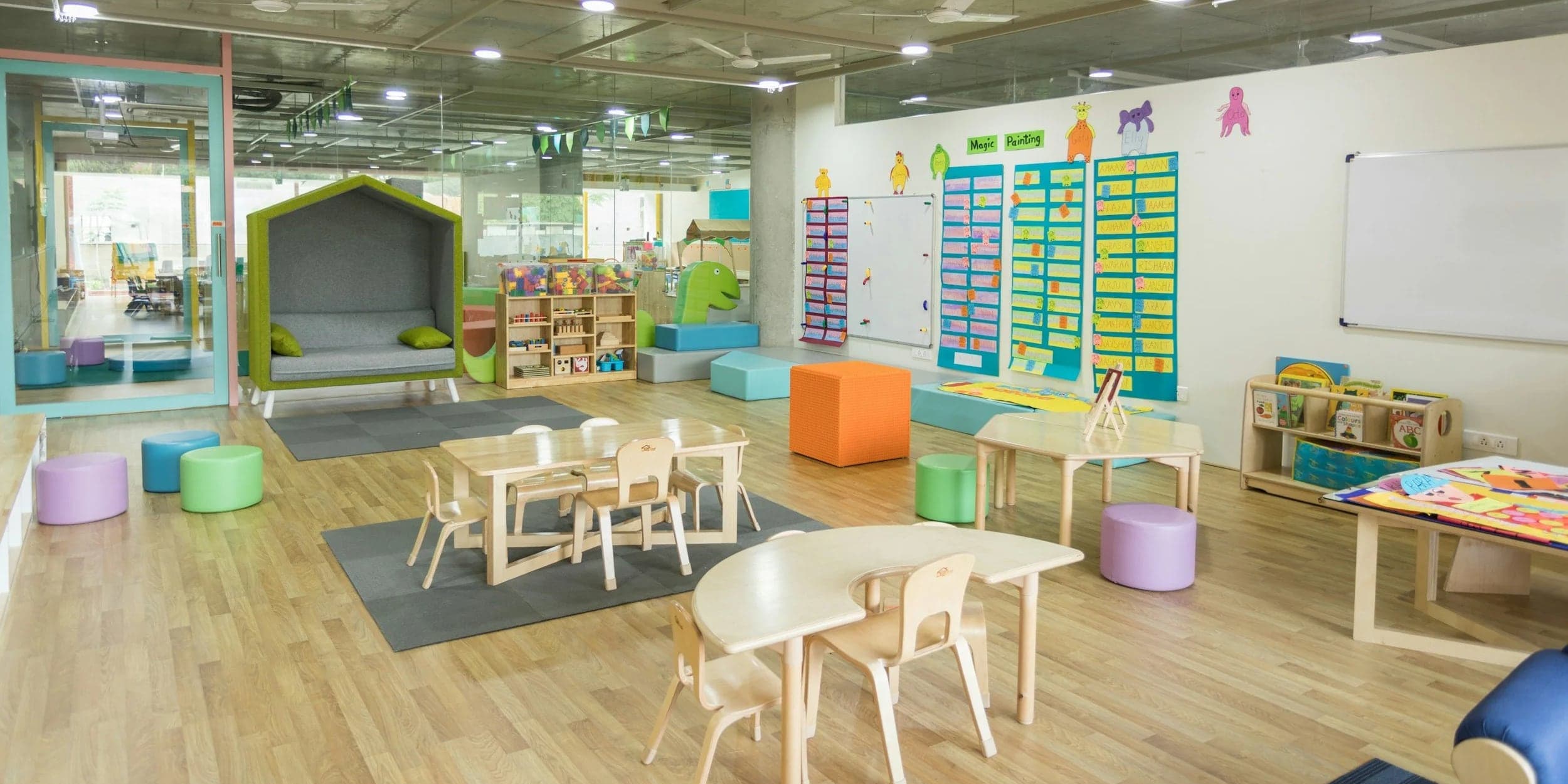A bright early learning classroom with child-sized tables, a reading nook and colourful seating
